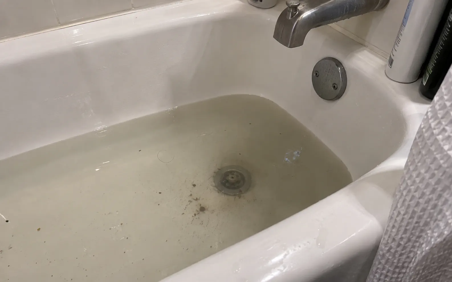 Bathroom tub drain with standing water caused by hair and soap residue