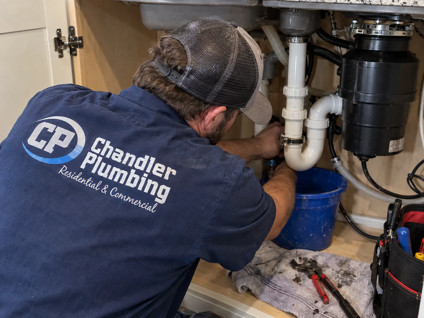 Chandler Plumbing plumber servicing a drain trap under a sink