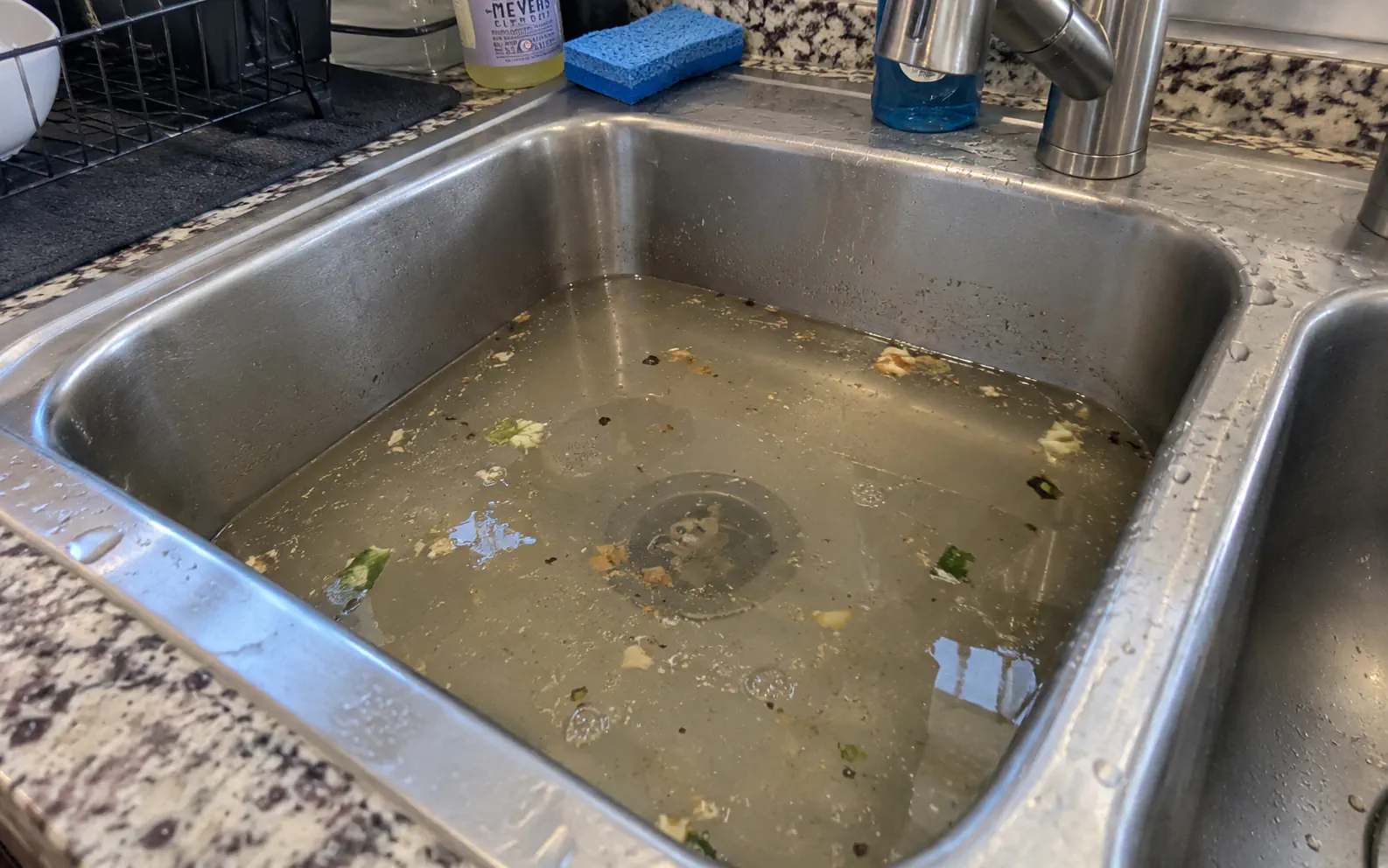 Kitchen sink with standing water caused by grease and food buildup